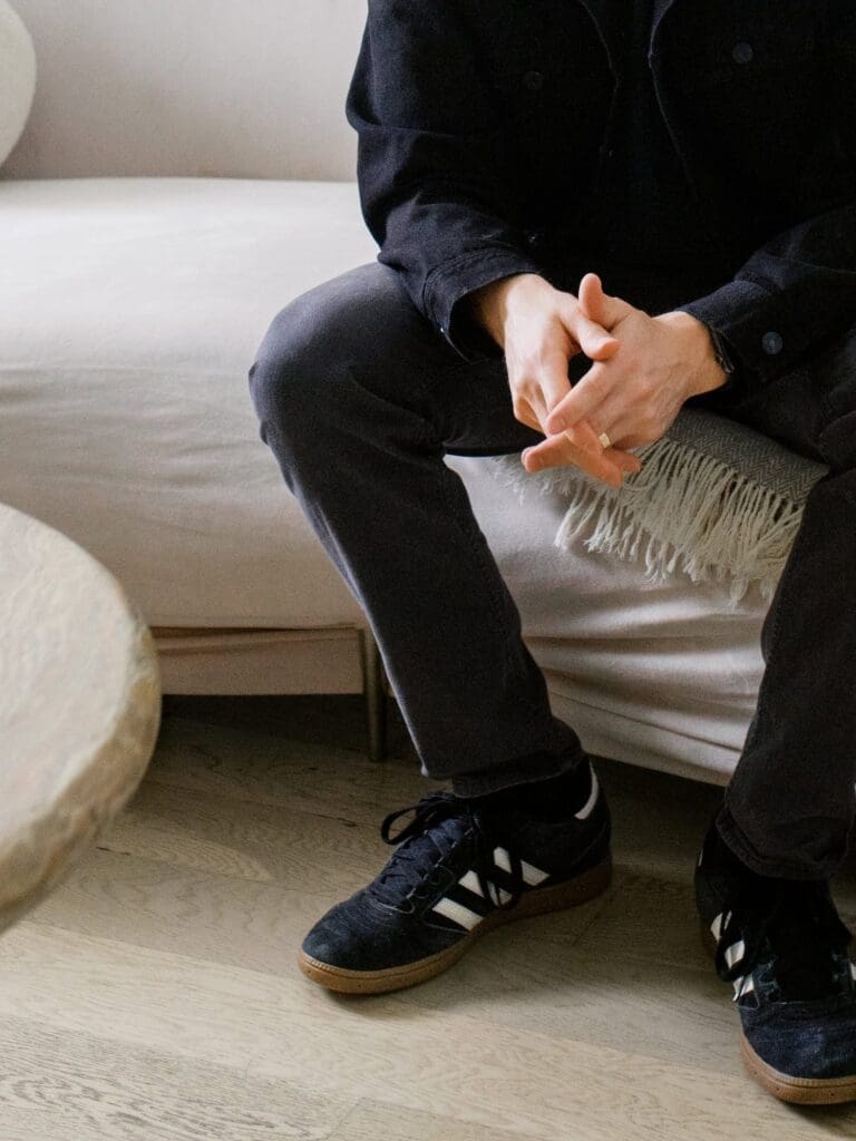 A counselor sits forward with clasped hands in a counseling office.