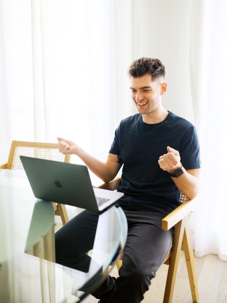A counselor smiles and gestures while seated at a laptop.